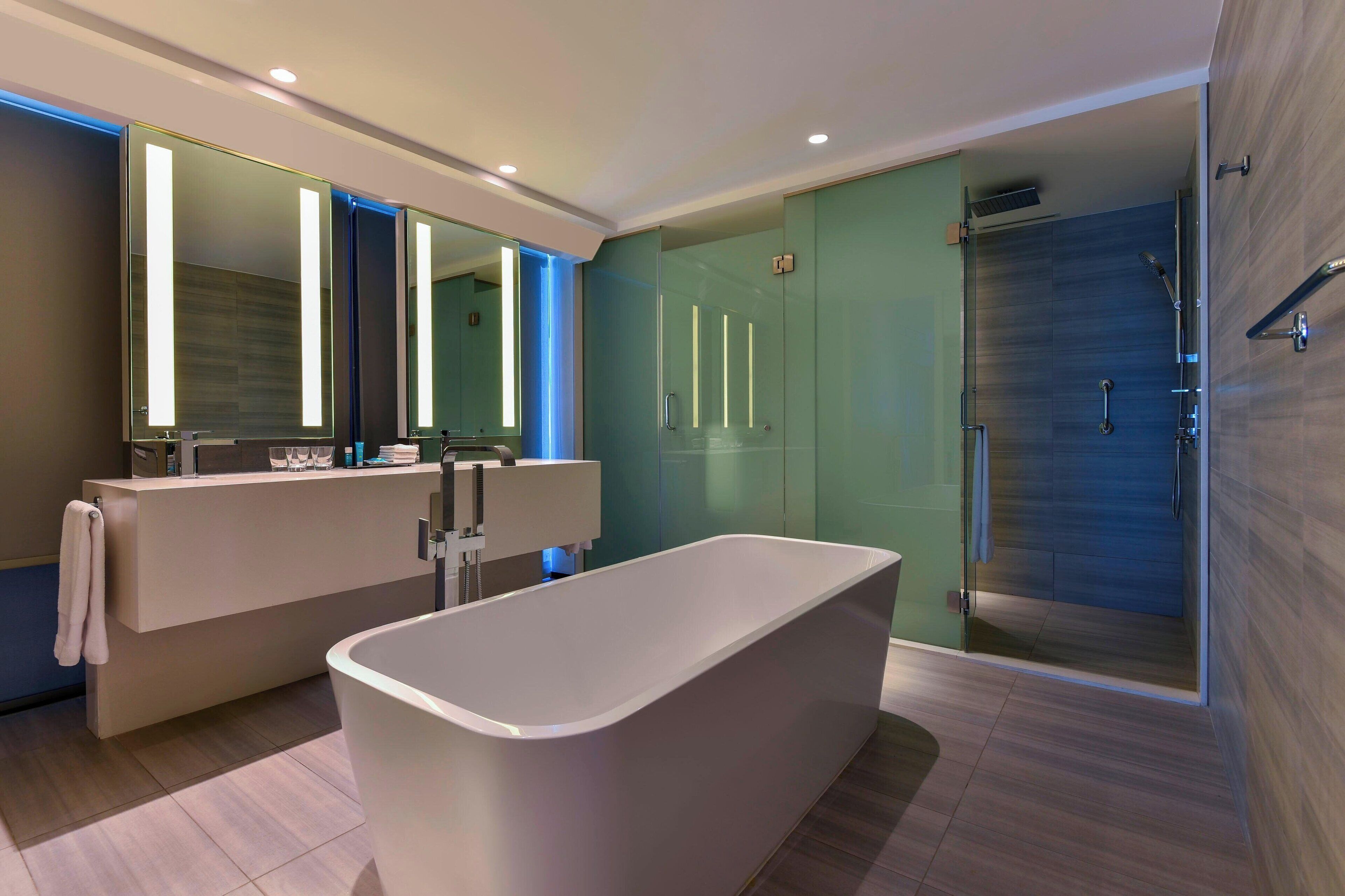 A modern bathroom with a freestanding bathtub, a large mirror, and a glass-enclosed shower area.