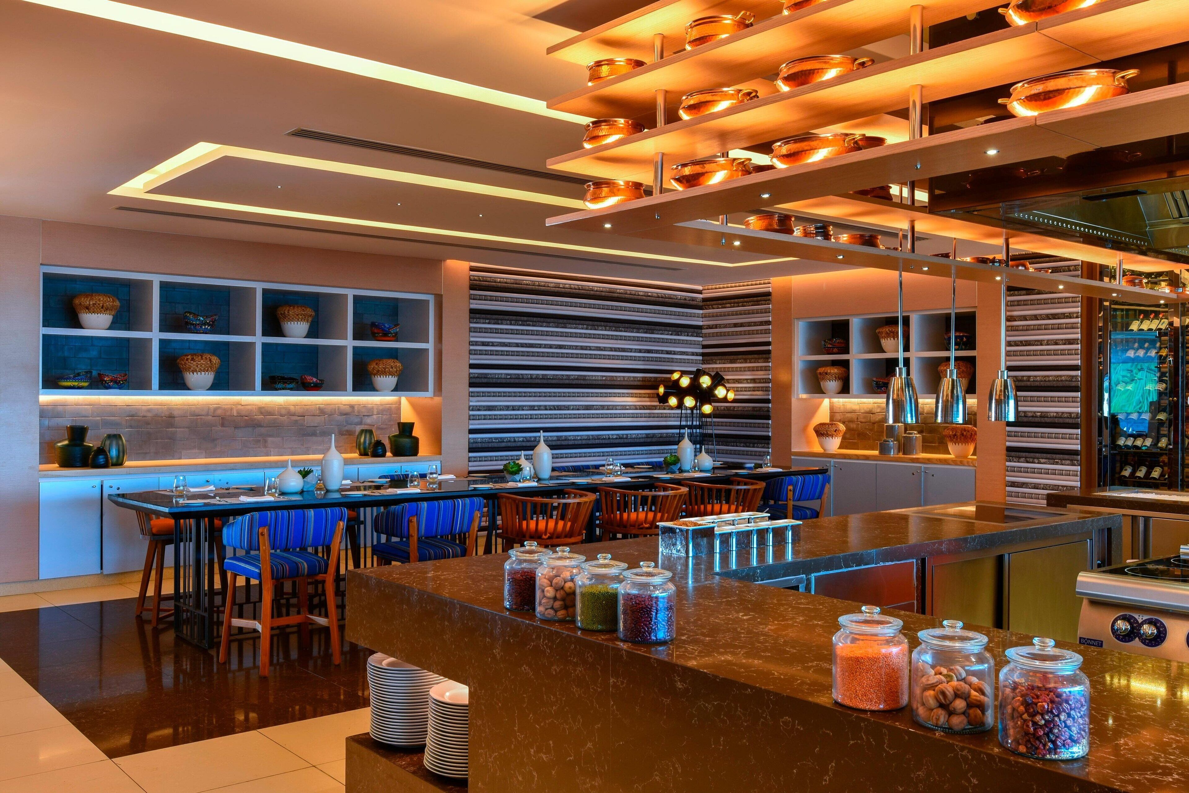 A modern kitchen with a central island, bar seating, and a variety of jars on the counter.