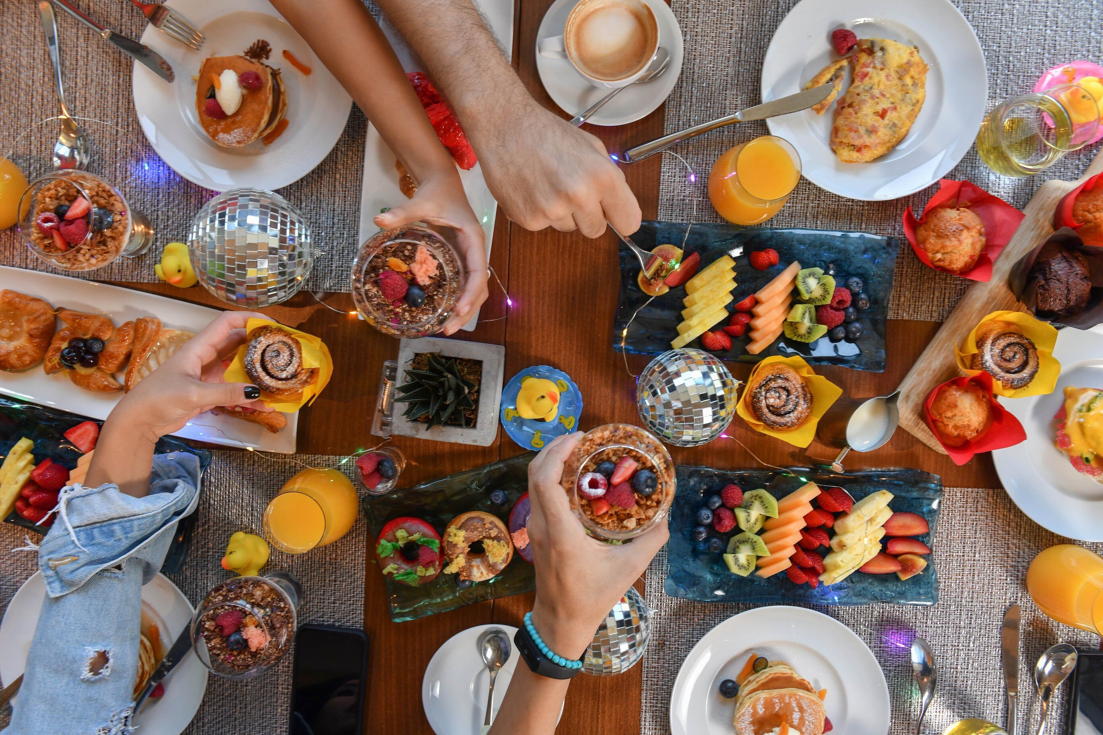 Une table dressée avec des aliments pour le petit-déjeuner, notamment des crêpes, des fruits et du café.