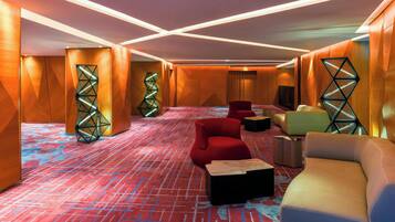 Un moderno vestíbulo de hotel con diseños geométricos en las paredes, asientos mullidos y una alfombra estampada.