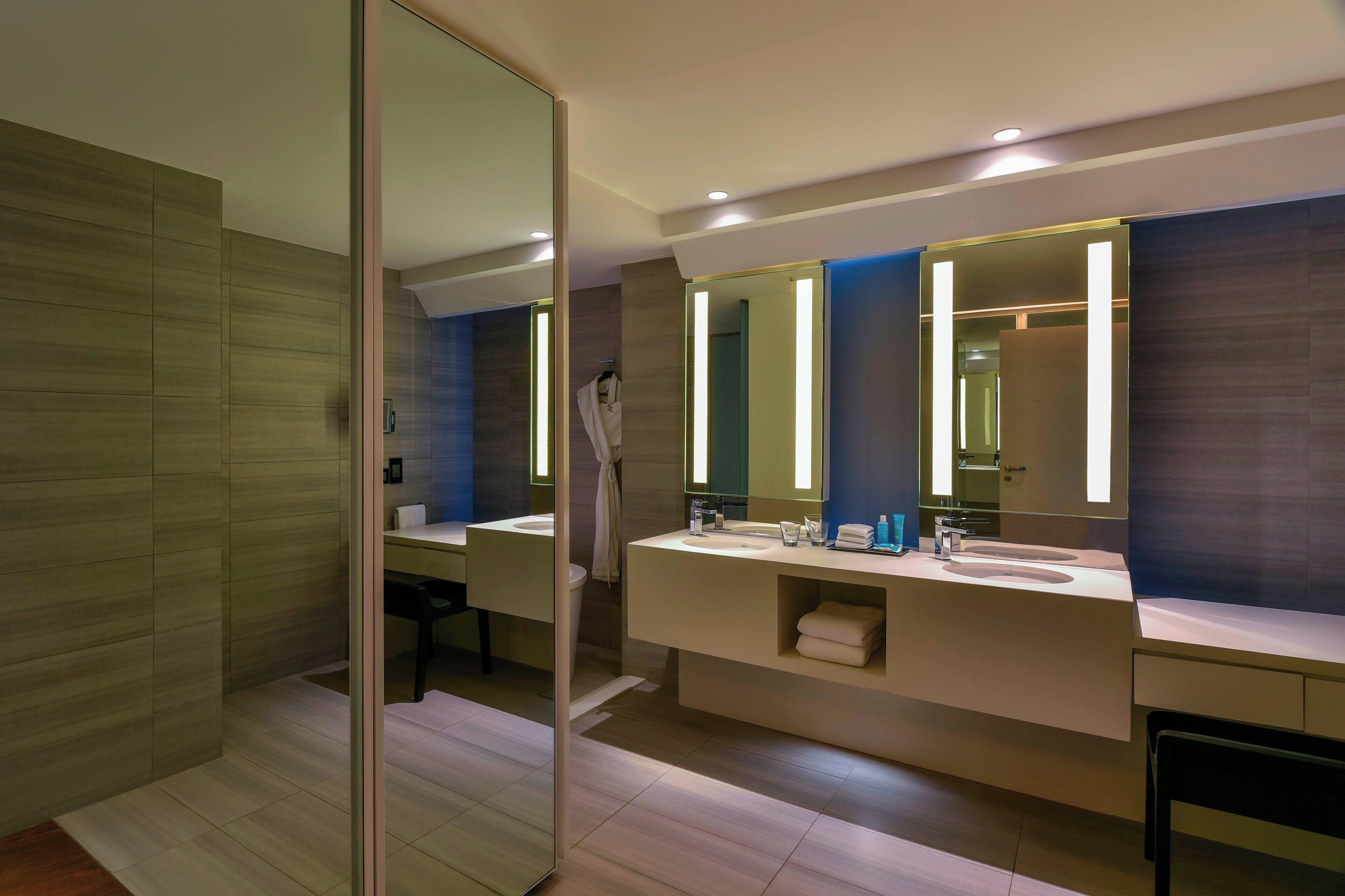 A modern bathroom with a large mirror, two sinks, and a towel rack.