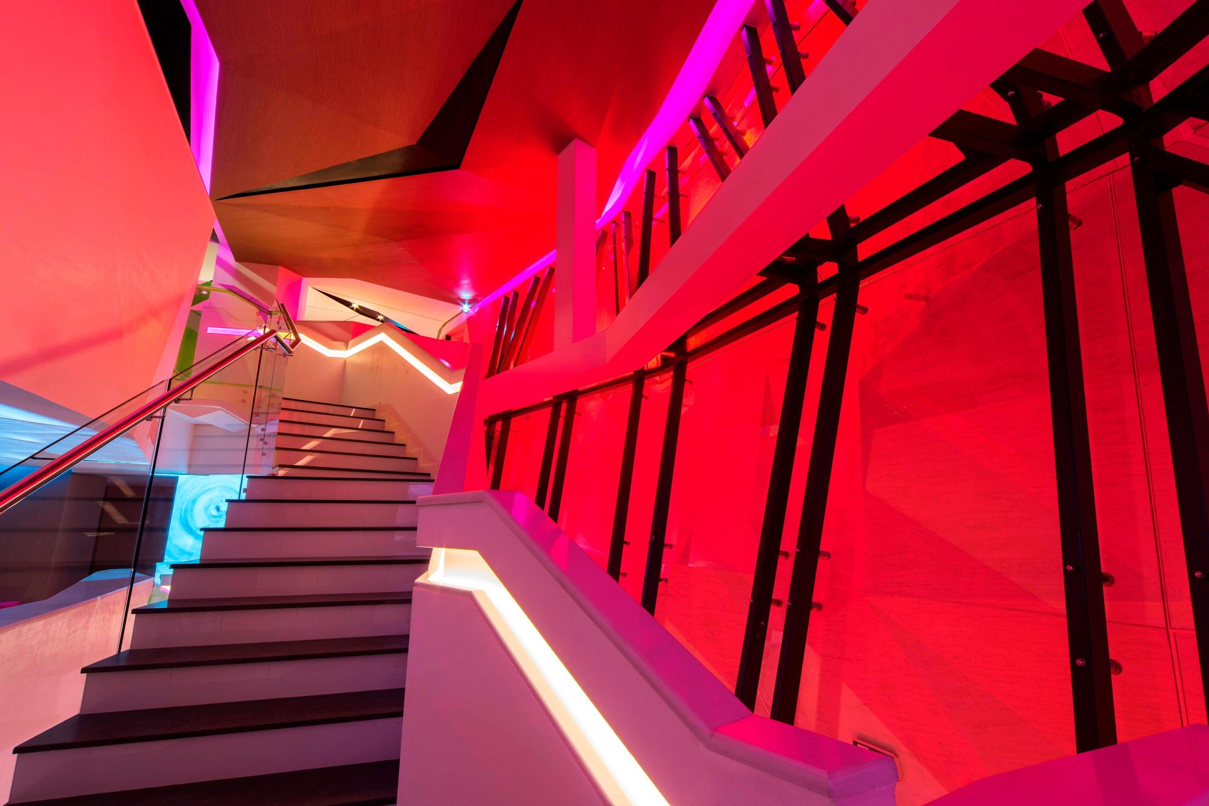 A modern staircase with glass railings and a red-lit interior.
