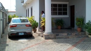 A two-story building with a balcony, a car parked in front, and potted plants. - Chateau De Trybze (Abuja)