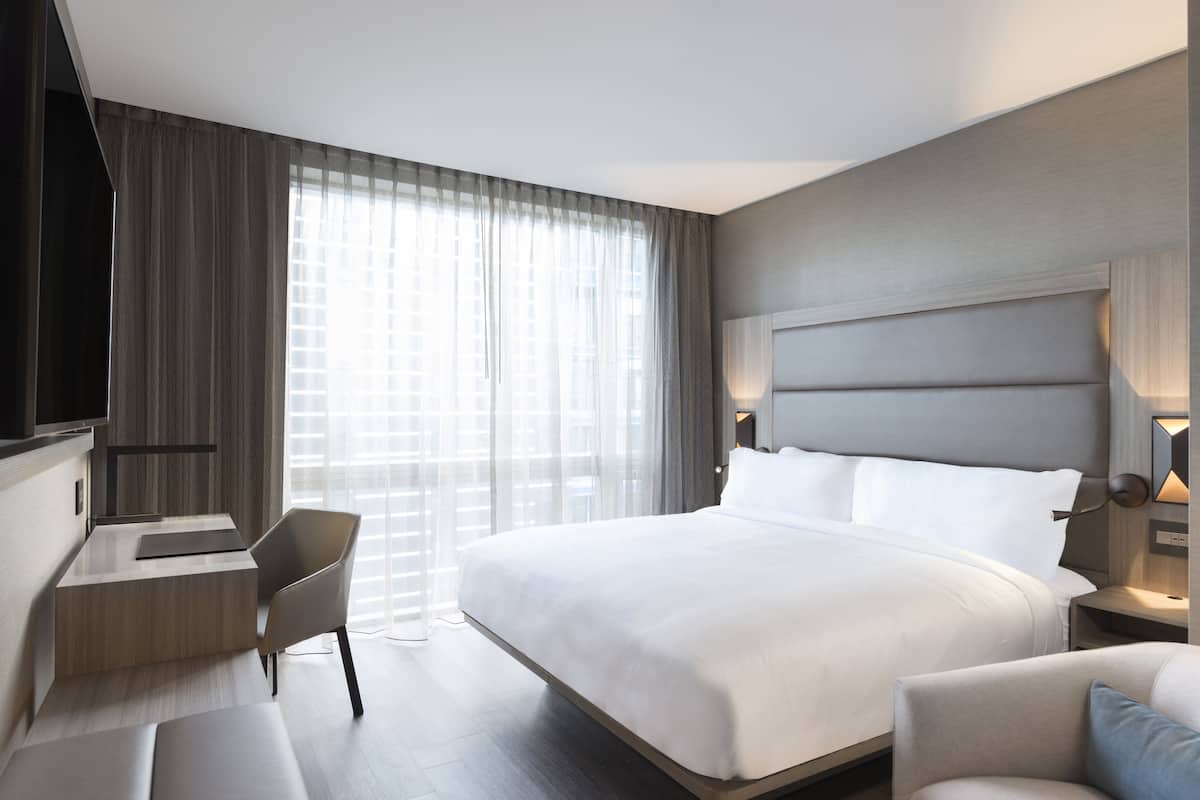 Una habitación de hotel moderna con una cama grande, un escritorio y una silla.