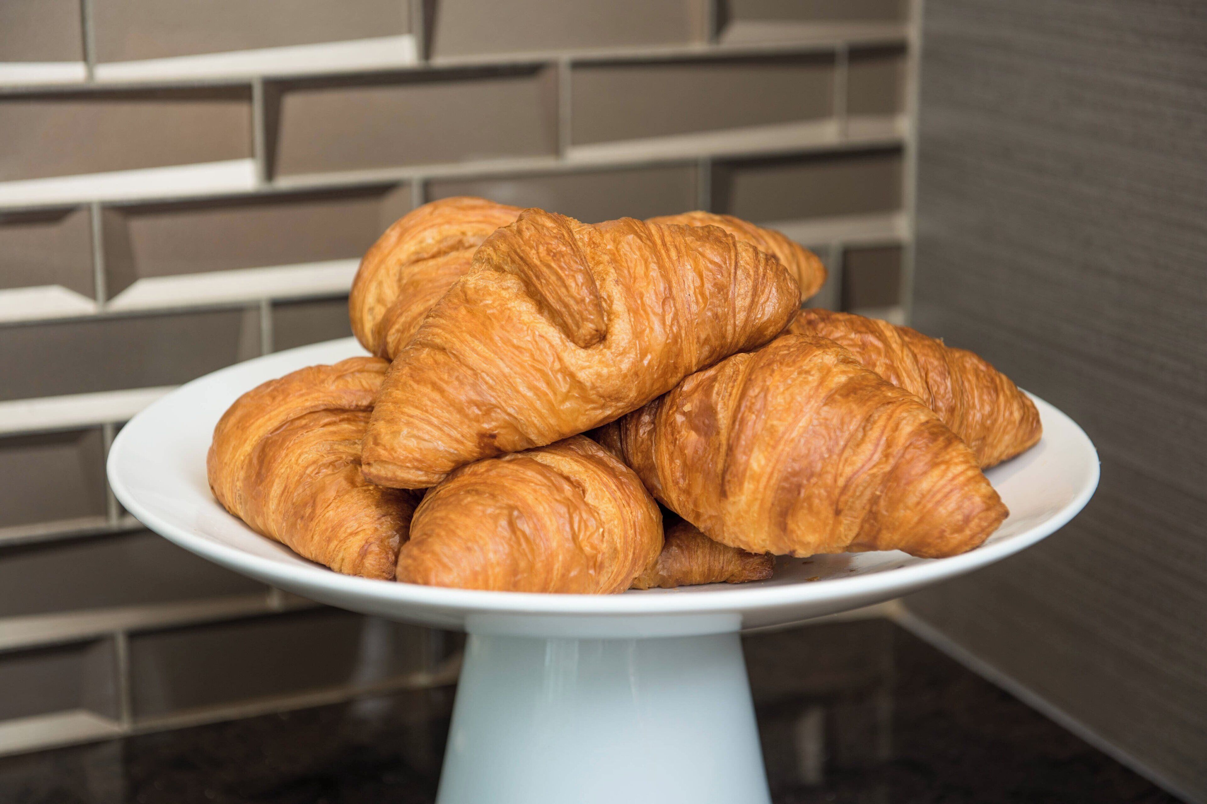 A plate of croissants on a white stand.