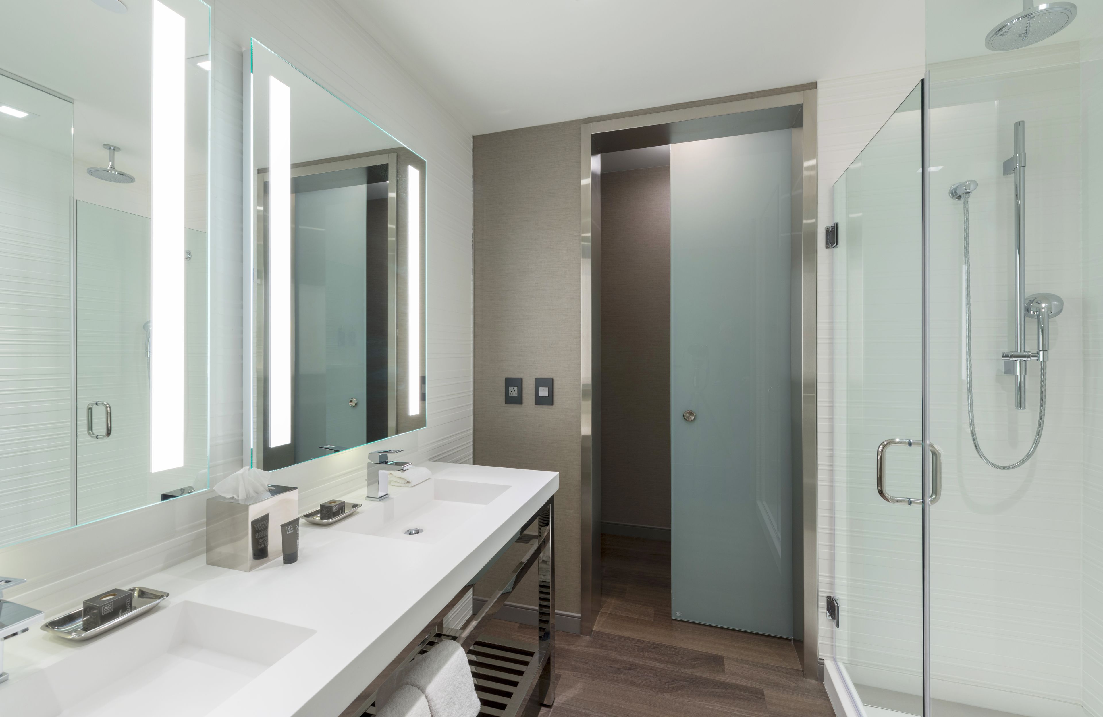 A modern bathroom with a glass-enclosed shower, a vanity with a mirror, and a walk-in closet.