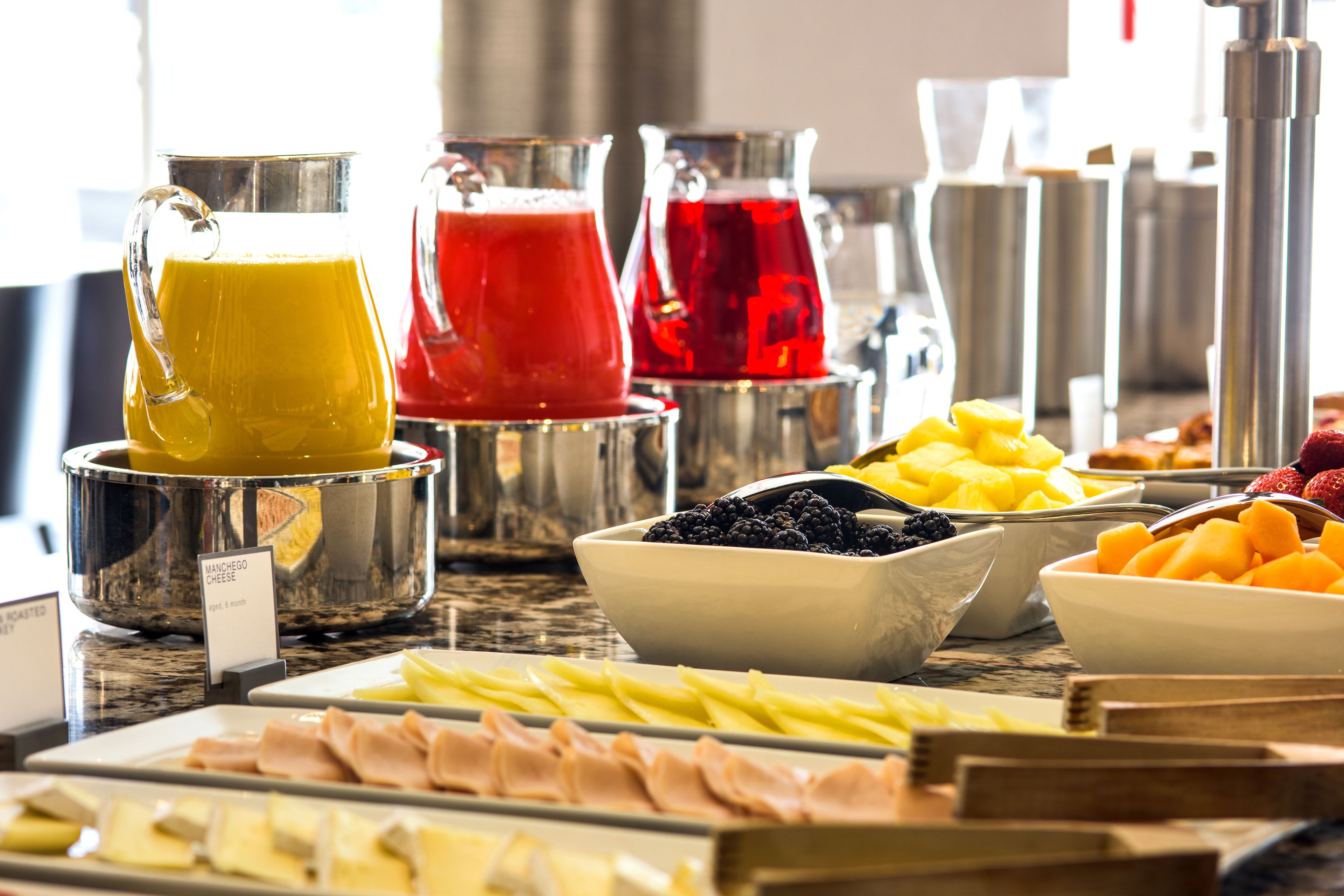 A buffet with various food items including fruits, cheeses, and meats.