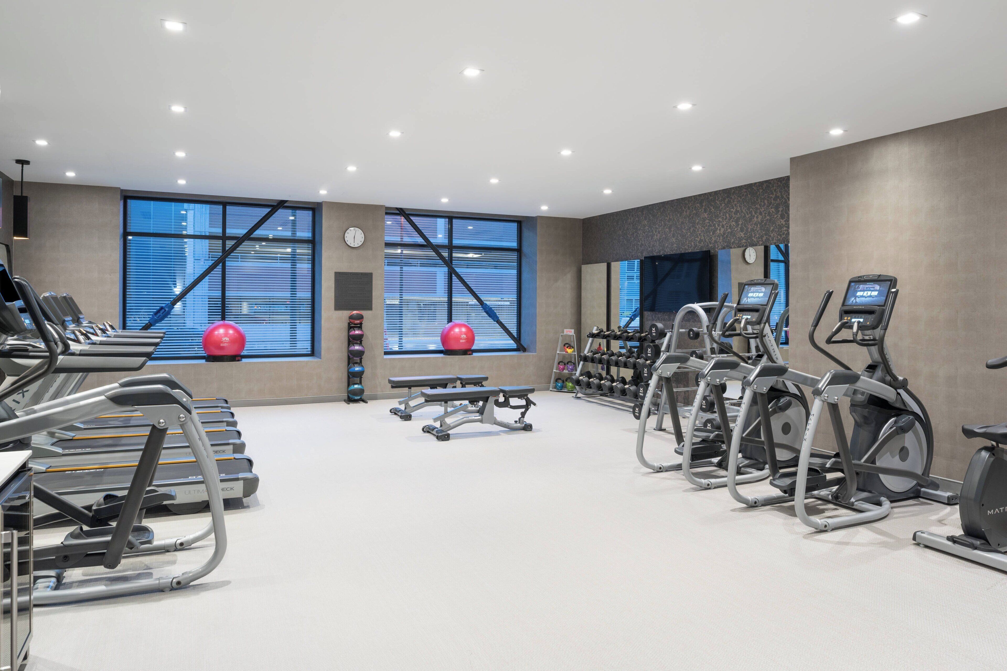 Un gimnasio moderno con cintas de correr, elípticas y pesas libres.
