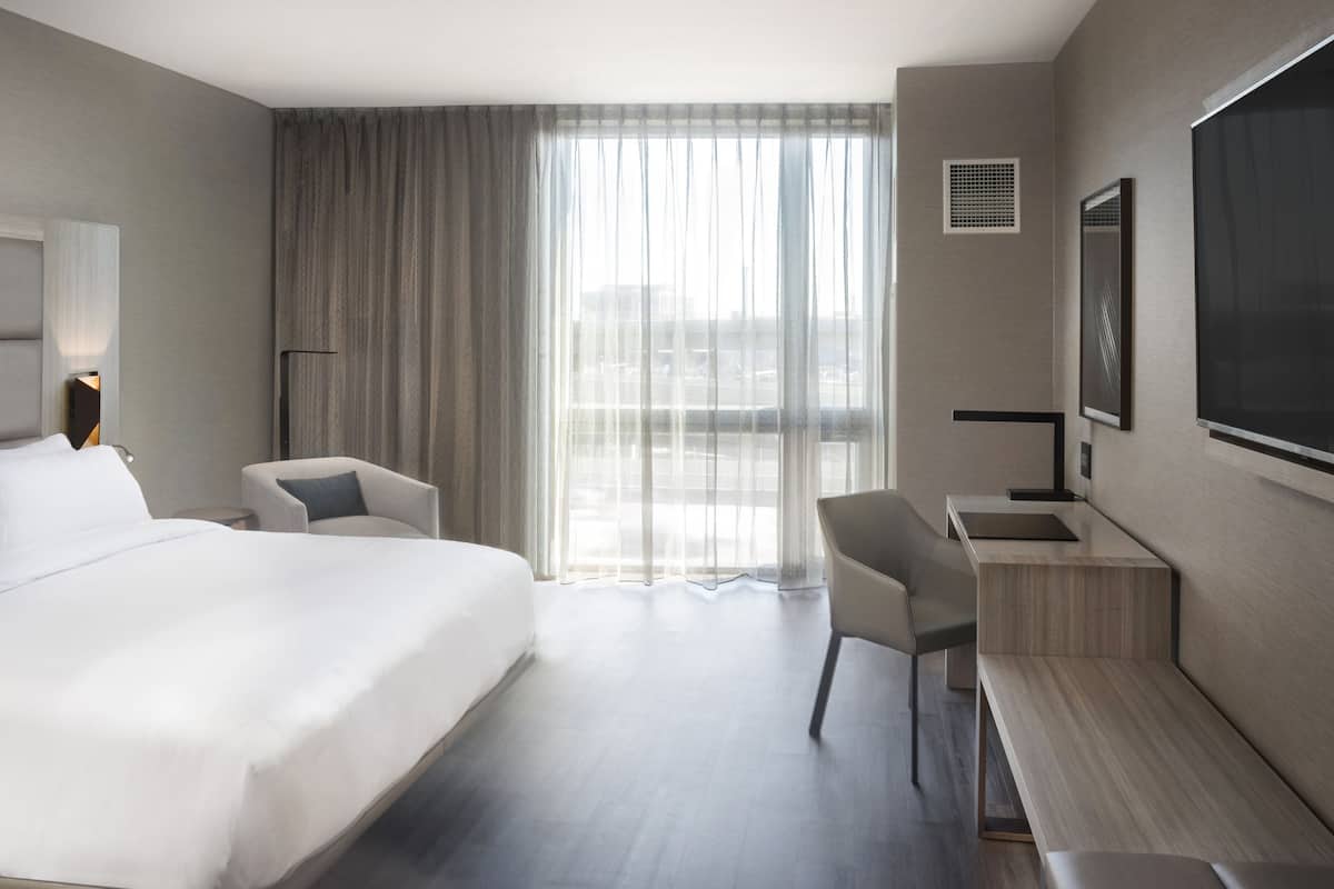Una habitación de hotel moderna con una cama grande, un escritorio y una silla.