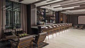 A modern bar area with leather seating, a long counter, and a large screen.