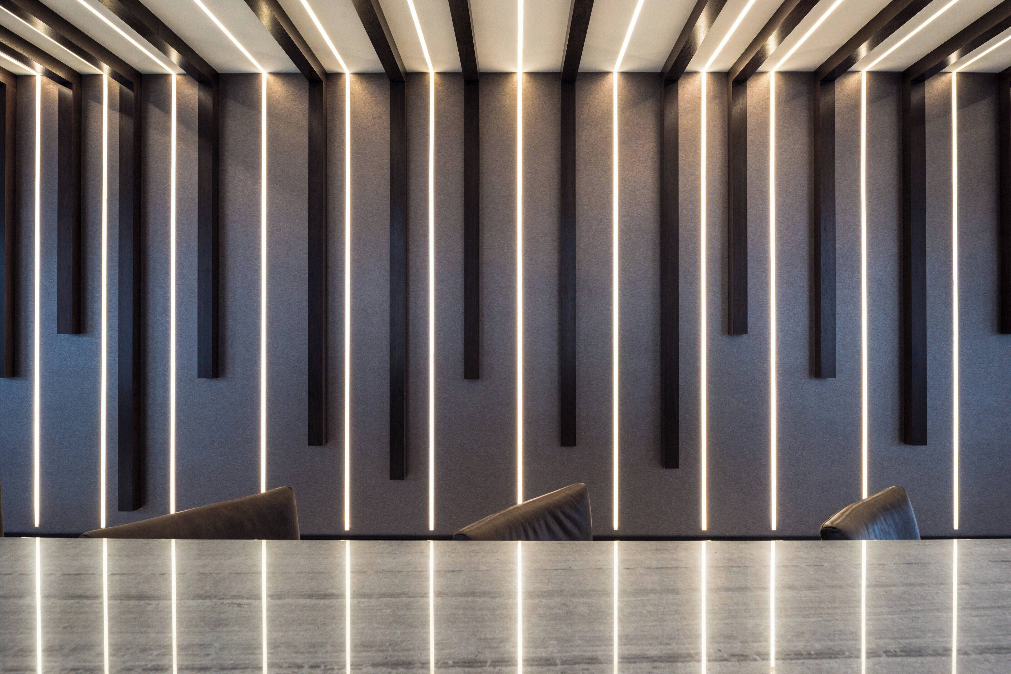 A modern conference room with a long table and chairs, illuminated by vertical light strips on the walls.
