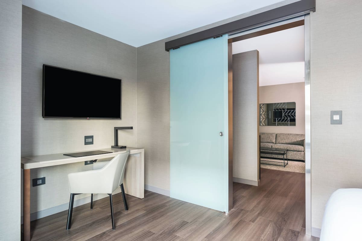 Habitación moderna con escritorio, silla y televisor fijado a la pared.