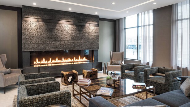 A modern living room with a fireplace, comfortable seating, and a large window.