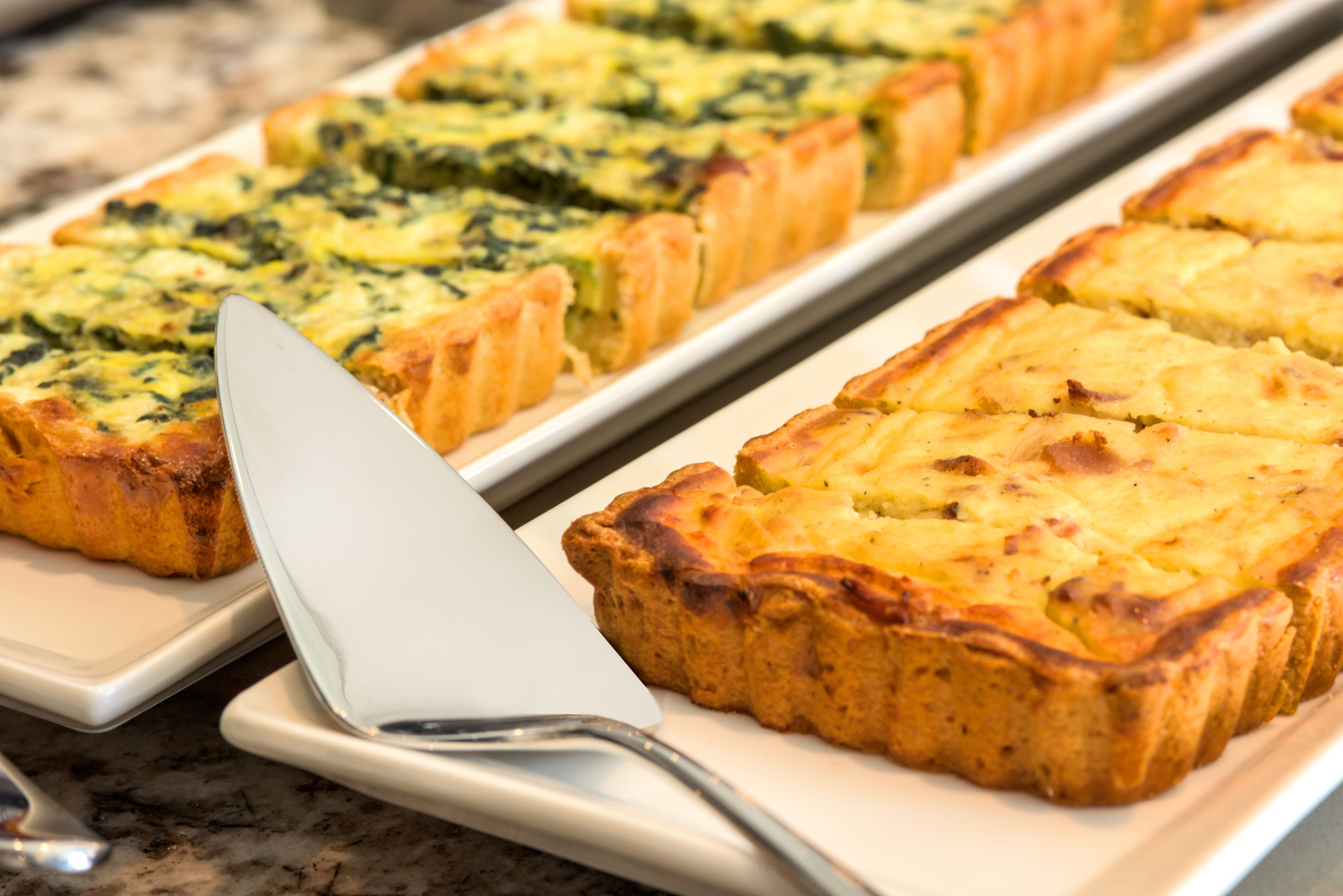 Uma travessa de quiches sobre um balcão de mármore.
