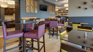 A modern restaurant interior with bar seating, a flat-screen TV, and decorative wall art. - Drury Inn & Suites Pittsburgh Airport Settlers Ridge (Pittsburgh)