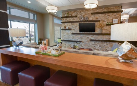 A modern bar area with a stone wall, flat-screen TV, and bar stools.