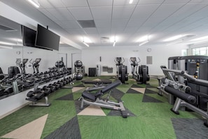 Un gimnasio con equipo de ejercicio, un espejo grande y un reloj.