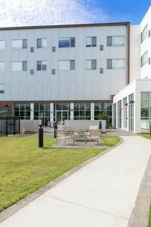 A modern building with a flat roof, large windows, and a paved walkway. - Element by Marriott Bentonville (Bentonville)
