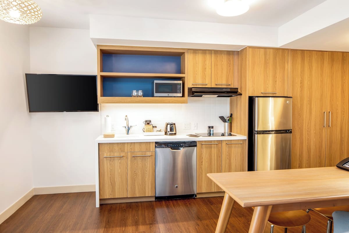 A modern kitchen with wooden cabinets, a stainless steel dishwasher, a microwave, and a refrigerator.