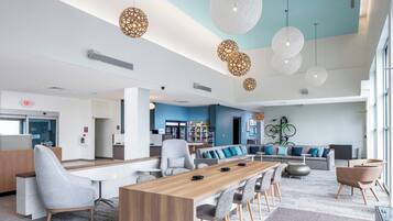 A spacious lobby with a long wooden reception desk, comfortable seating, and modern pendant lighting.