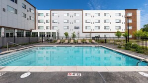 A swimming pool with a no diving sign, surrounded by a fence, and adjacent to a multi-story building with a modern design. - Element by Marriott Bentonville (Bentonville)