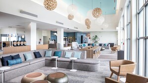 A spacious hotel lobby with a large seating area, a bar, and large windows. - Element by Marriott Bentonville (Bentonville)