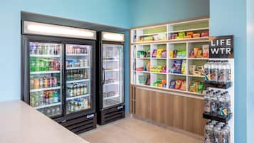 A room with two refrigerators stocked with beverages, shelves with snacks and drinks, and a sign that reads 'LIFE WTR'.