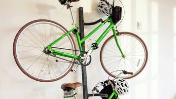 A green bicycle with a brown seat and a helmet hanging on the wall.