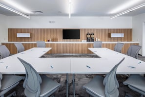 A conference room with a long table, six chairs, a mounted TV, and a wooden accent wall.
