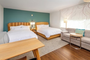 A hotel room with two beds, a sofa, a small table, and a lamp.