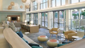 A spacious lobby with a large seating area, a central table, and large windows offering views of the outside. - Element by Marriott Bentonville (Bentonville)