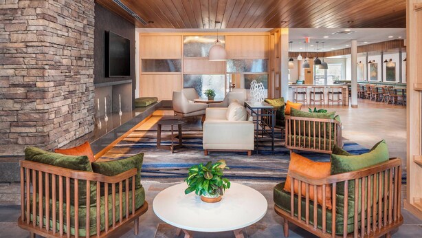 A spacious lobby with a stone wall, wooden ceiling, and a central seating area with a round table and chairs. - Fairfield Inn & Suites by Marriott Lebanon (Lebanon)