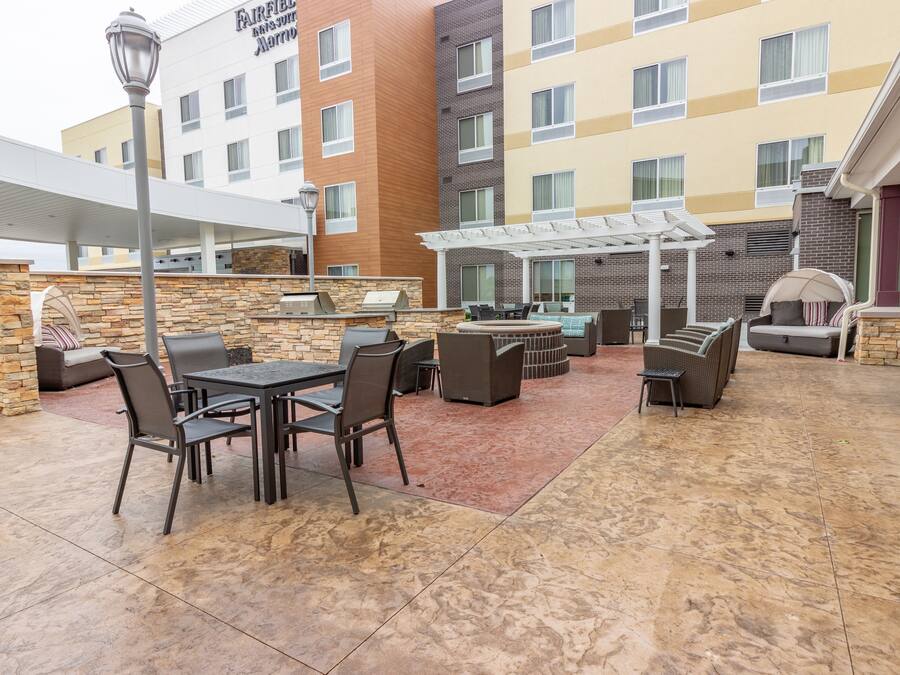 Un patio al aire libre con pared de piedra, una parrilla y mobiliario exterior.
