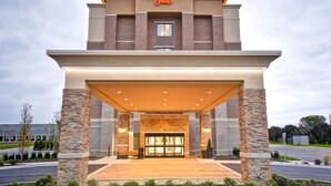 A Hampton Inn hotel entrance with a brick facade, a covered entrance area, and a clear sky. - Hampton Inn Livonia Detroit (Livonia)
