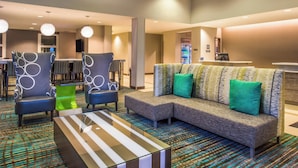 A modern hotel lobby with a sectional sofa, two armchairs, a glass coffee table, and a patterned carpet. - Residence Inn St Louis Westport (Maryland Heights)
