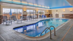 An indoor swimming pool with lounge chairs and tables, large windows, and a clock on the wall. - Residence Inn St Louis Westport (Maryland Heights)