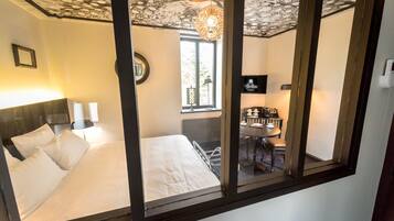Een hotelkamer met een bed, een bureau met stoel, een raam en een plafond met bloemendesign.