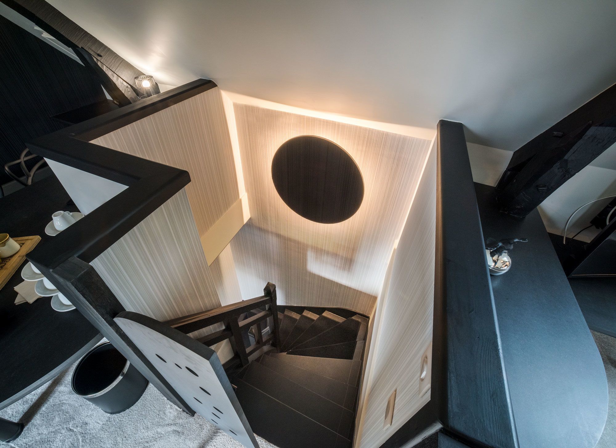 A modern staircase with a circular light fixture at the top, leading to a lower level.