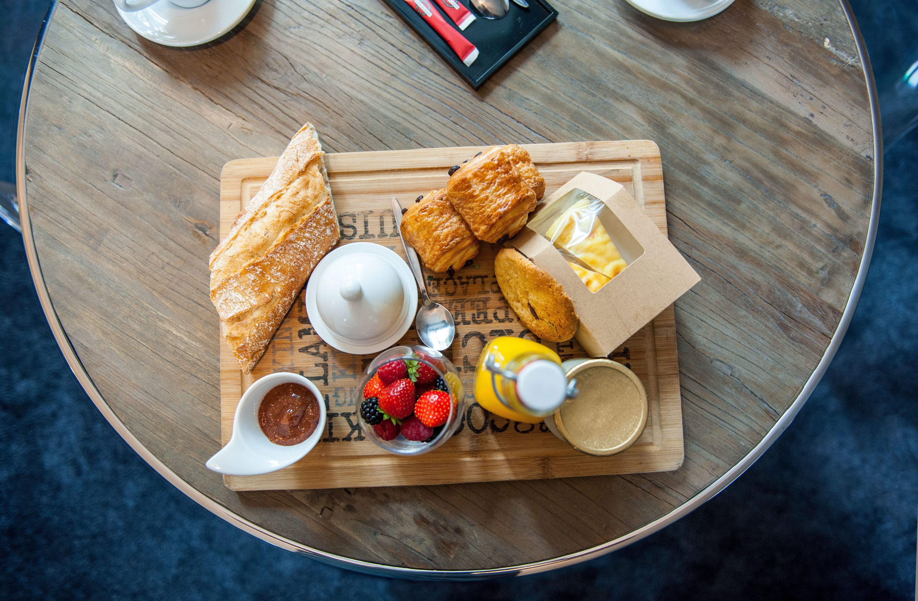 Una mesa de madera con diversas opciones de desayuno, como pasteles, frutas y salsas.