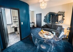 Un salón moderno con una mesa redonda de vidrio, un sofá gris y un espejo decorativo.