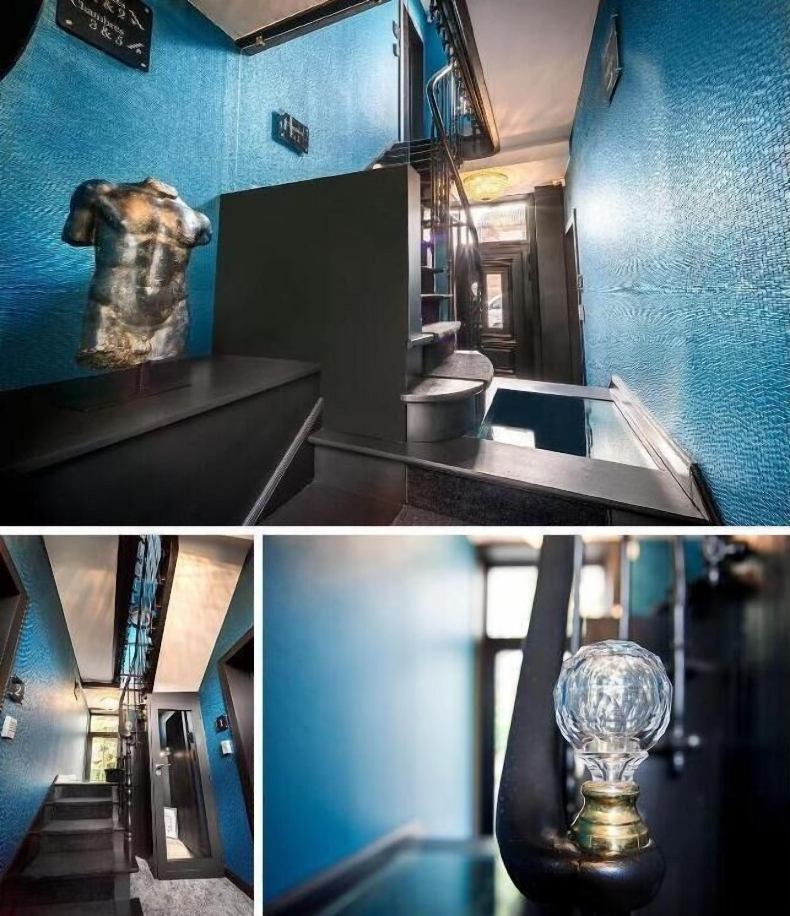 Un couloir d’hôtel moderne avec un mur bleu à texture, une sculpture et un objet décoratif en verre.