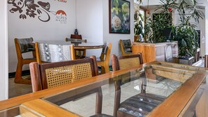 A dining area with a glass-top table, wooden chairs, and a reception desk with a plant. - Ayenda 1080 Bogota Alpes Castellana (Bogotá)