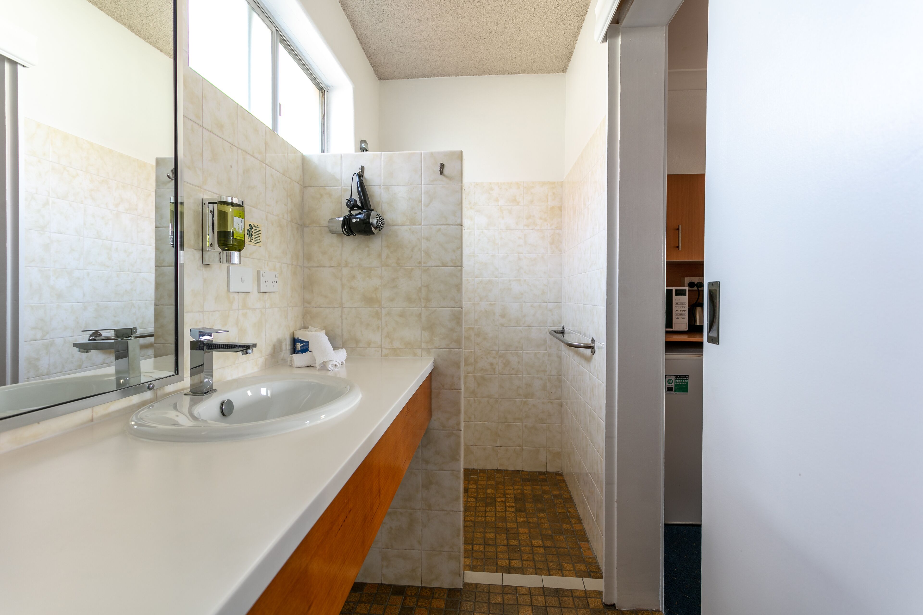 Un baño moderno con un espejo grande, lavamanos blanco y zona de ducha.