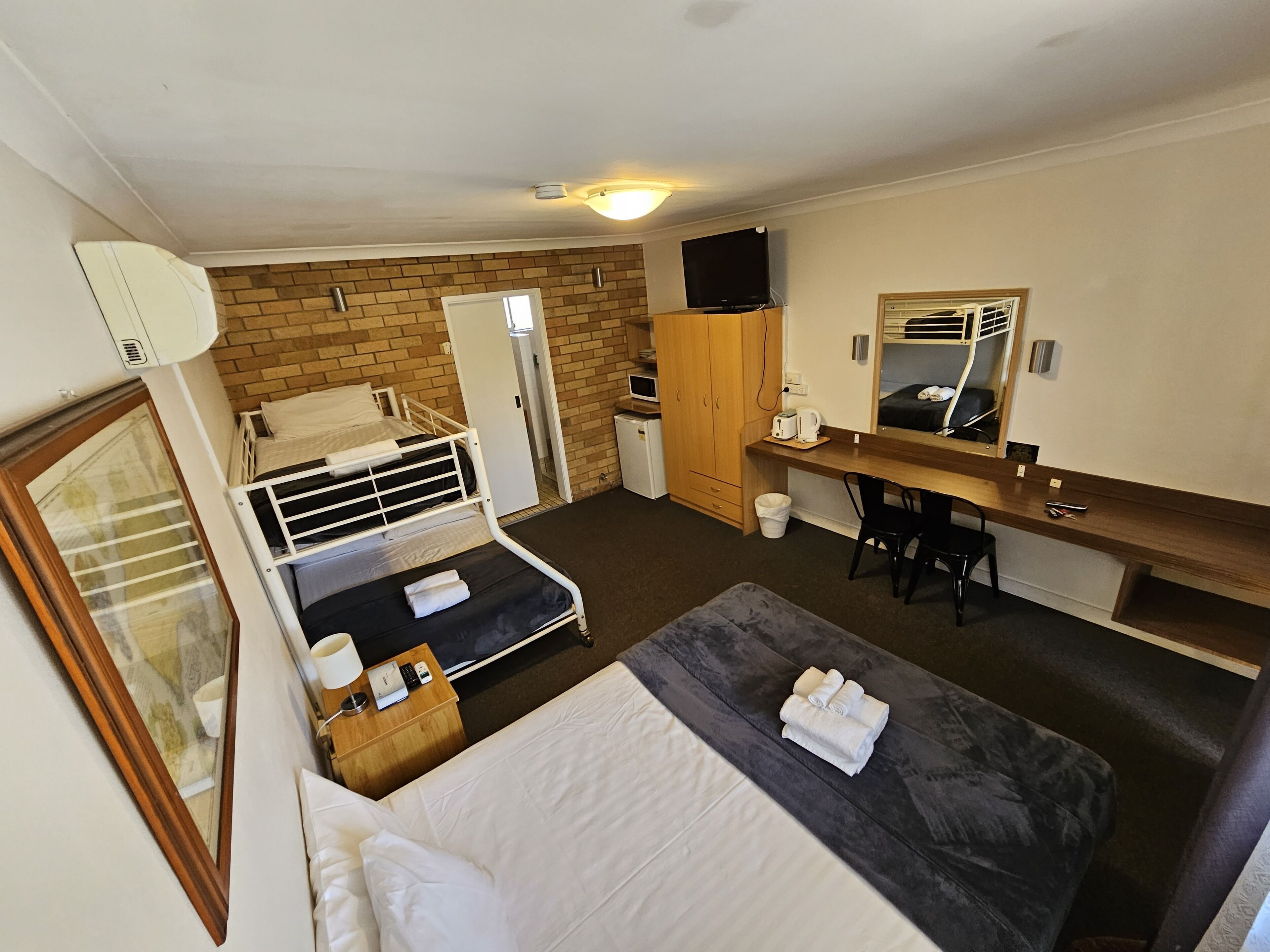 Una habitación de hotel con cama, escritorio, silla, armario y televisión.