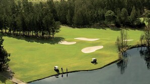 A golf course with sand bunkers, a pond, and a forested area. - Hunter Valley Motel (Cessnock)
