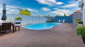 A backyard with a swimming pool, patio furniture, and a fence. - Hunter Valley Motel (Cessnock)