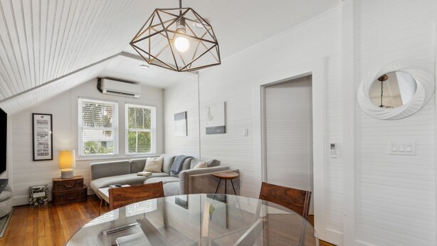 Un salon moderne avec une table à manger en verre, un luminaire suspendu aux formes géométriques et un canapé confortable.