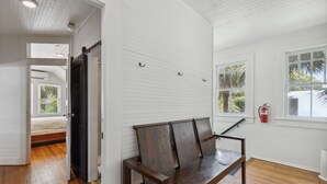 Une pièce avec un banc en bois, des murs blancs et une fenêtre donnant sur des palmiers.