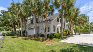 A two-story house with a front porch, surrounded by palm trees and a well-maintained lawn. - Stanton Apartment C - Historic retreat 1 block to beach (Saint Simons Island)