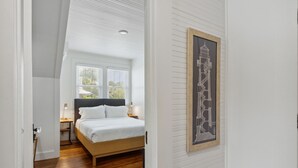 A bedroom with a bed, a nightstand, a lamp, and a framed architectural drawing on the wall. - Stanton Apartment C - Historic retreat 1 block to beach (Saint Simons Island)